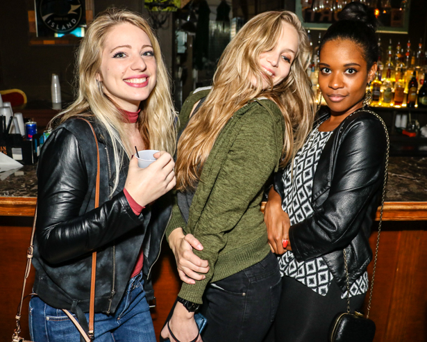 Two white girls and a black girl posing in front of a bar counter in Downtown Orlando.